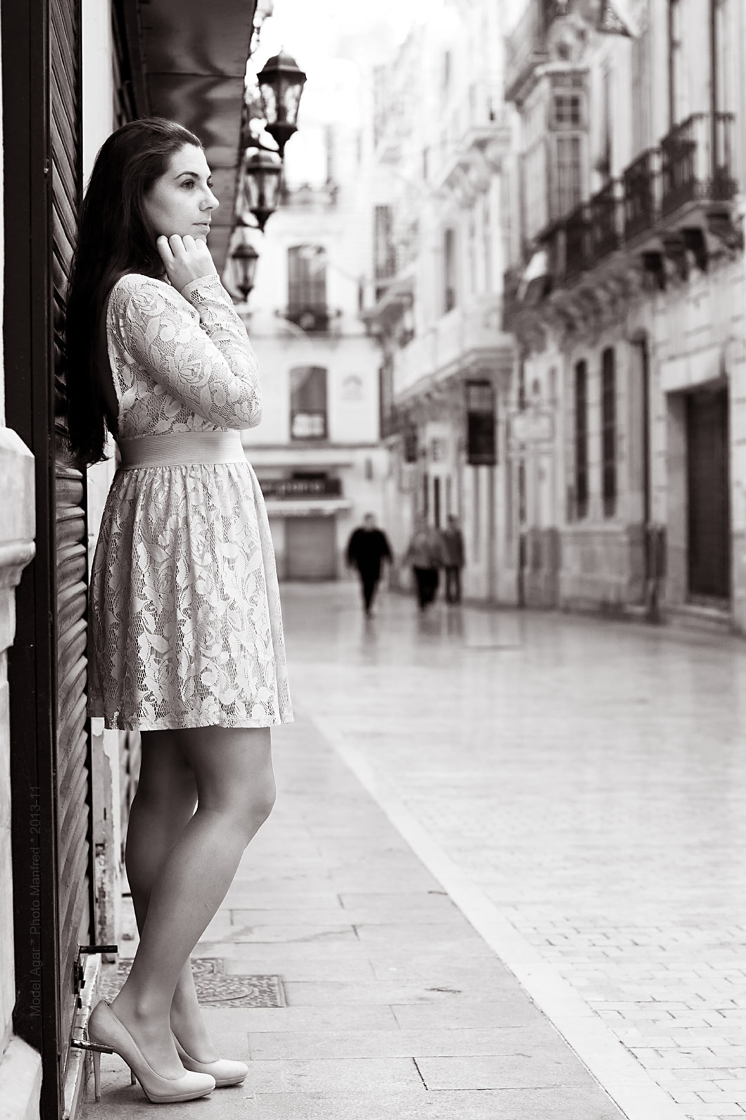 A young woman wearing a skirt is standing in a street in the centre of Málaga.