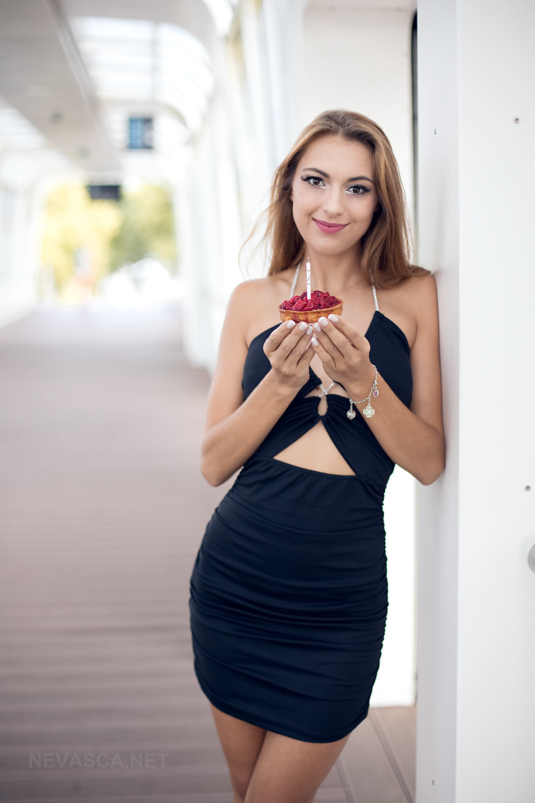A young woman is holding in her hands a birthday cake.